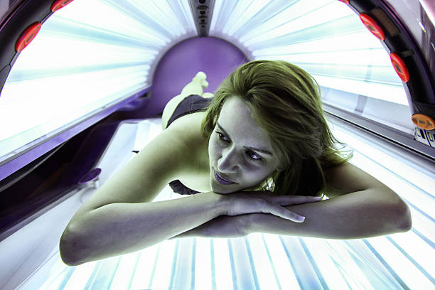 Woman in solarium Young beautiful woman lying on a tanning bed in a solarium. About 25 years old, Caucasian female in black bikini. tanning bed stock pictures, royalty-free photos & images