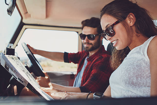 istock Young couple on roadtrip reading map for directions 517421828