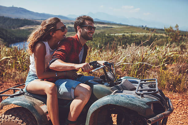 Couple having fun on an off road adventure Man and woman having fun on an off road adventure. Couple riding on a quad bike in countryside on a summer day. quadbike photos stock pictures, royalty-free photos & images