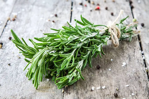 a bunch of fresh rosemary on a wooden background