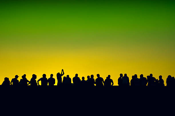 istock people silhouettes event with yelow and green sky 517443245