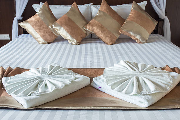 istock nice towels on white bed sheet with golden pillow 517443739
