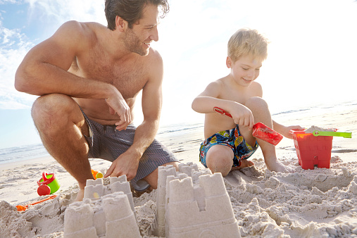 Shot of a young father and son building a sandcastle on the beach