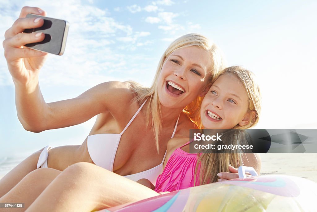 Vacation memories with mom Cropped shot of a young mother and daughter taking a picture of themselves on a beach Adult Stock Photo