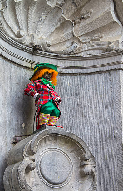 Manneken Pis dressed as a clown red. Manneken Pis dressed as a clown red. This is an old Brussels tradition to dress this statue in various funny closes. manneken pis statue in brussels belgium stock pictures, royalty-free photos & images