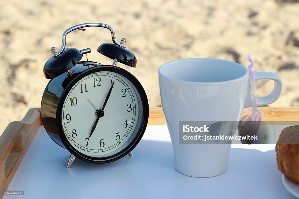 alarm clock and cup of coffee on the beach Alarm Clock Stock Photo