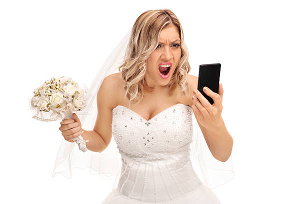 Furious bride looking at her cell phone Furious young bride looking at her cell phone and screaming isolated on white background bride stock pictures, royalty-free photos & images