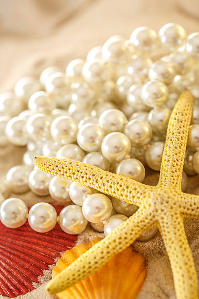 istock White pearl and seashells on sand 517462094