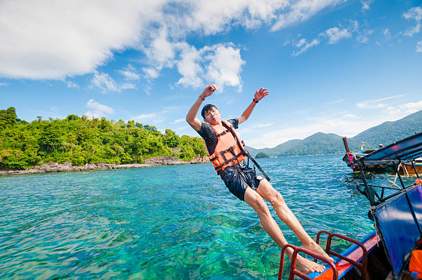istock Man jumping off the boat into the ocean 517465700