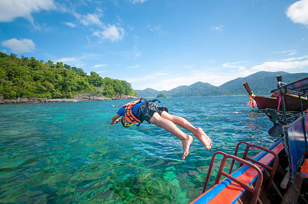 istock Man jumping off the boat into the ocean 517465832