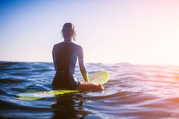 surfer girl surfer girl sitting on surfboard in ocean, sunset. longboarding stock pictures, royalty-free photos & images