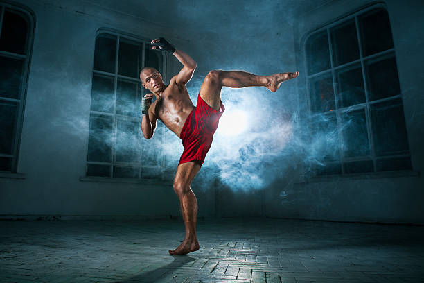 istock The young man kickboxing in blue smoke 517467358