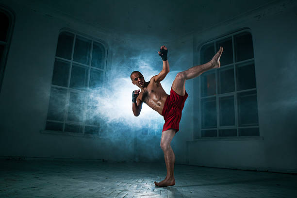 istock The young man kickboxing in blue smoke 517467474