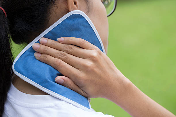 woman putting an ice pack on her neck pain woman putting an ice pack on her neck pain ice pack photos stock pictures, royalty-free photos & images