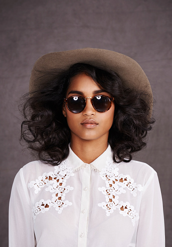Cropped shot of a stylish young woman posing in sunglasses and a hat