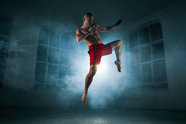 istock The young man kickboxing in blue smoke 517468420