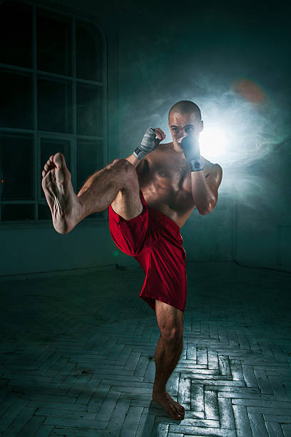 istock The young man kickboxing in blue smoke 517469470