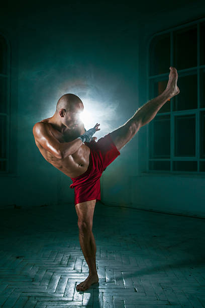 istock The young man kickboxing in blue smoke 517469616