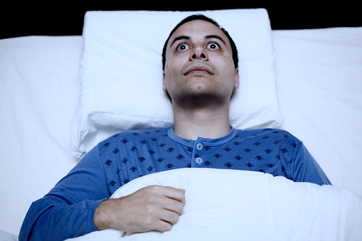 Portrait of an insomniac man trying to sleep