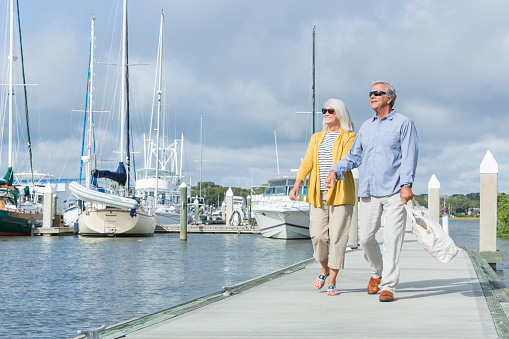 Happy senior couple walking along harbor holding hands