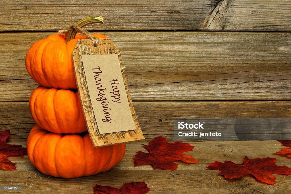 Mini pumpkins with Happy Thanksgiving tag on wood Stack of mini pumpkins with Happy Thanksgiving tag on a wooden background Arrangement Stock Photo