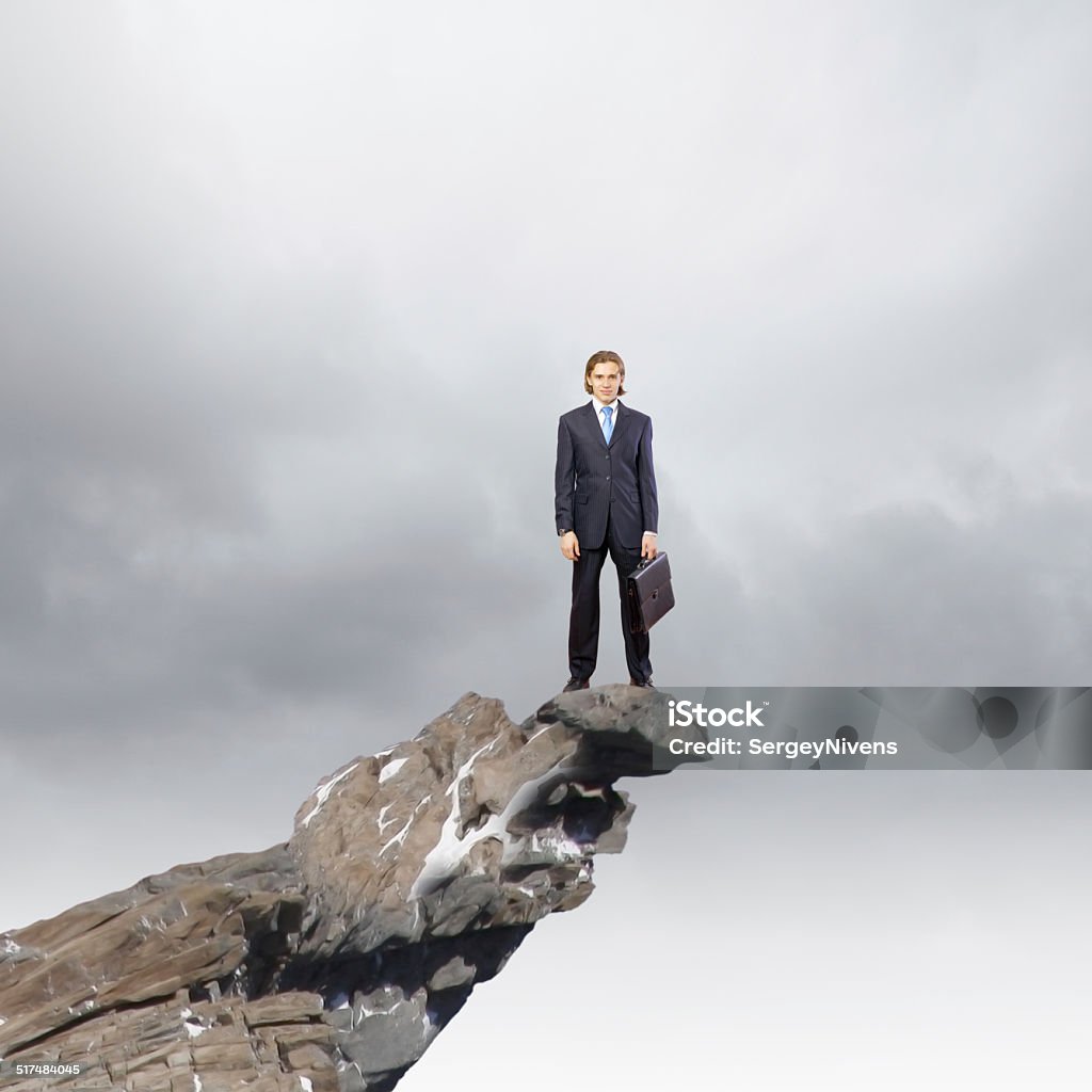 Risk in business Young businessman standing on edge of rock mountain Adult Stock Photo