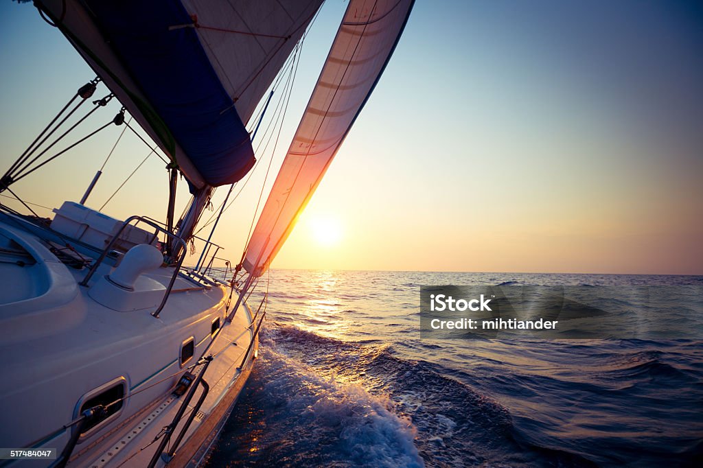 Sail boat Sail boat gliding in open sea at sunset Sailboat Stock Photo