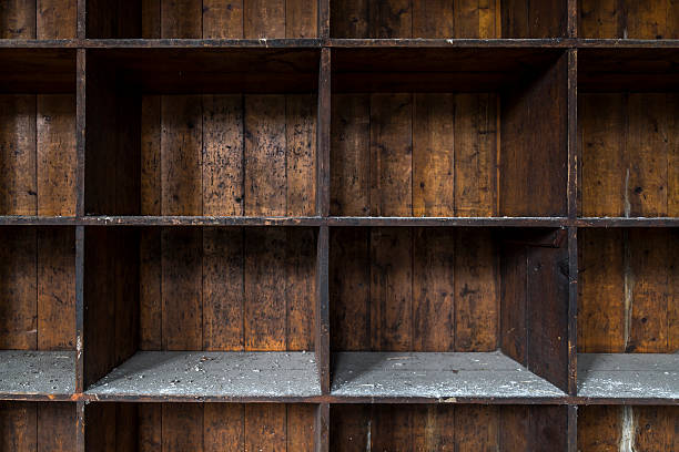 An old and distressed, dark wood shelf. Made of empty boxes covered with dust and dirt.