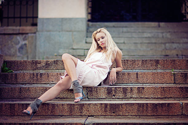 Sad, fashion blonde girl is sitting on the stairs