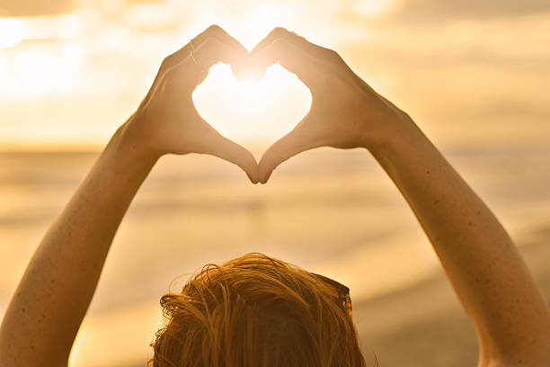 istock Heart symbol made with hands on the beach 517488261