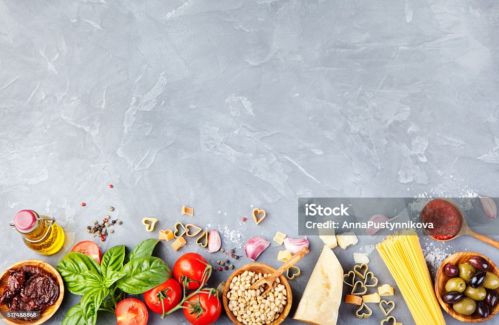 Italian food background on stone table Copy space Top view Italian food background with vine tomatoes, basil, spaghetti, olives, parmesan, olive oil, garlic Ingredients on stone table Copy space Top view Backgrounds Stock Photo