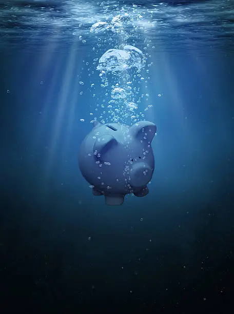 Piggy bank drowning in the ocean with copy space