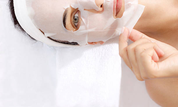 Facial Mask Caucasian female is taking off facial mask. facial mask beauty product stock pictures, royalty-free photos & images