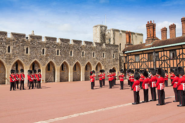 Windsor, United Kingdom - June 29, 2015: Changing the Guard at Windsor Castle, Berkshire England. Royal Guards wearing vivid red uniform and carrying rifles and Regimental Band, Corps of Drums and a Pipe Band are in the image. Windsor castle was built in the 11th century and is the longest-occupied palace in Europe.