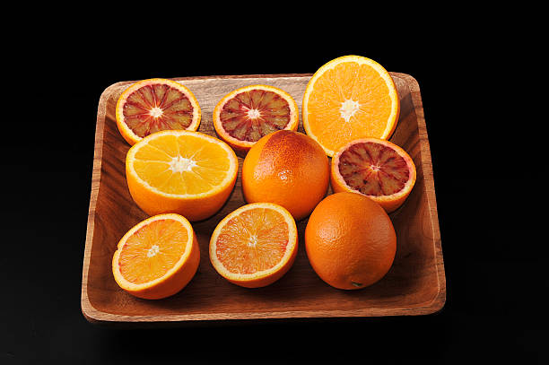 istock oranges whole and cut in half on a wood tray. 517496432