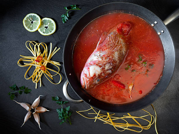 Sorpionfish Tomato Sauce Preparing red scorpionfish sauce for the fettucine pasta, typical Italian recipe. Overhead shot of table with ingredients and pan with the fish and tomato sauce. red scorpionfish photos stock pictures, royalty-free photos & images