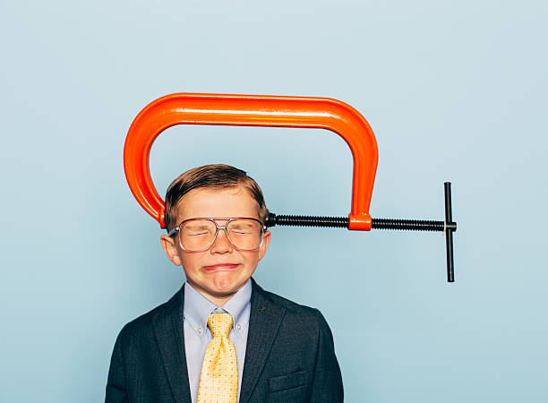 Young Boy Businessman In Pain with Vice on His Head A young business boy dressed in suit and wearing glasses is not responding well to business pressure. The c clamp on his head is causing him to grimace  under lots of pressure.  c clamp photos stock pictures, royalty-free photos & images