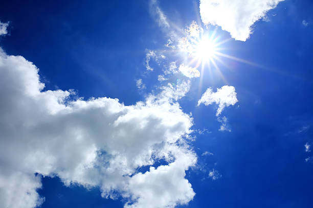 istock blue sky and sun with clouds closeup 517504263