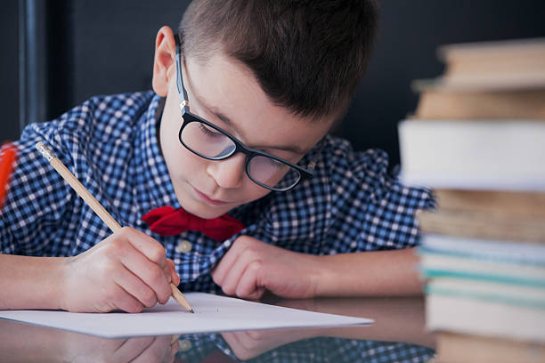 istock Beautiful boy with eyeglasses writing a homework 517514900