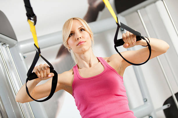 istock Athletic woman doing stretching exercises with suspension straps 517518652
