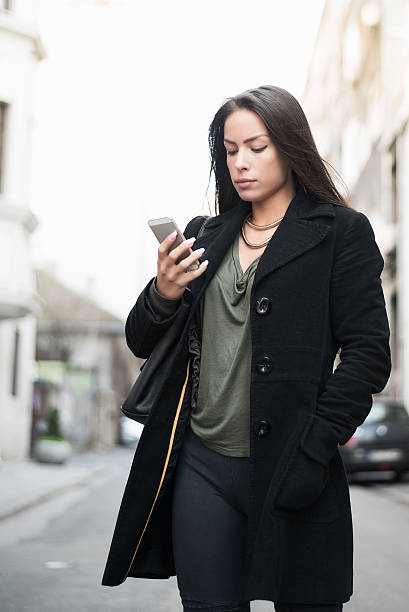 istock Business woman using a smartphone while walking the street. 517519136
