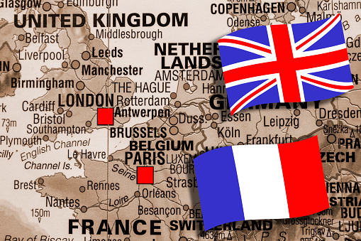 Map featuring Western European countries with focus on the cities of London, England and Paris, France.  French and United Kingdom flags on top of sepia colored map.   Many surrounding countries also shown.
