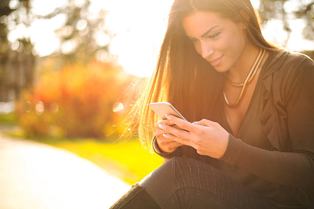 istock Beautiful woman using her smartphone outside 517520252