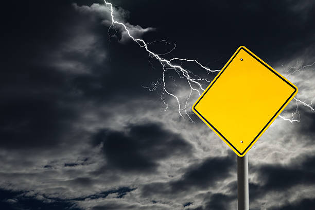 Empty Warning Sign Against Cloudy and Thunderous Sky An empty traffic sign against a dark, cloudy and thunderous sky. Conceptually warning of danger ahead. Blank sign for copy space and message. lightning storm natural disaster cloud stock pictures, royalty-free photos & images