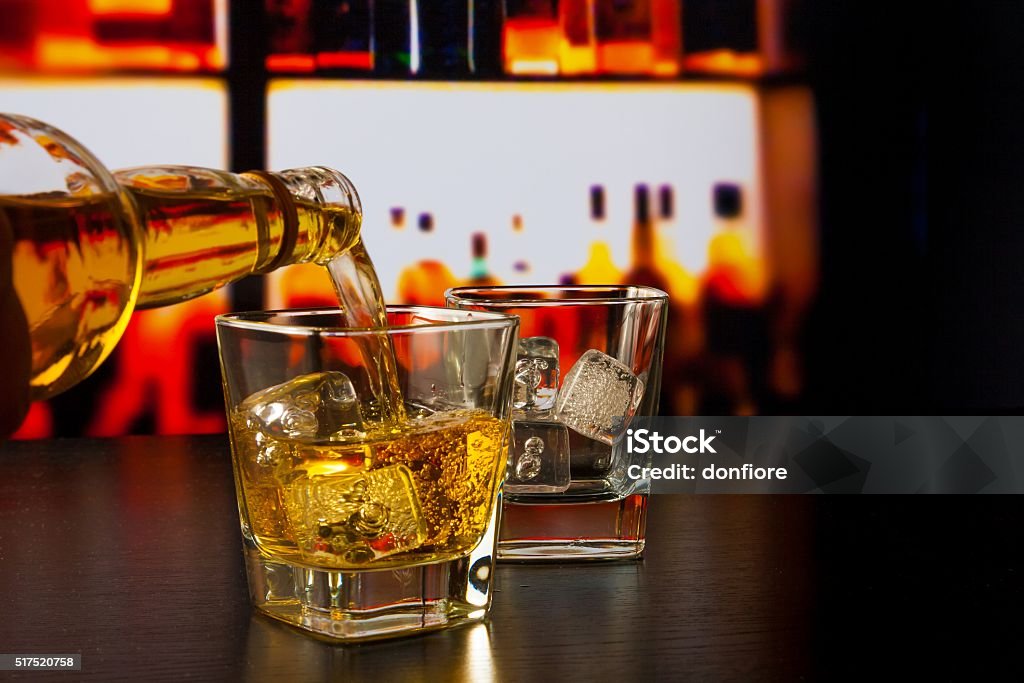 バーテンダーに注ぐウィスキーの前のウイスキーグラスやボトル - ウイスキーのロイヤリティフリーストックフォト