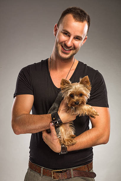 Handsome young man holding a yorkshire terrier dog