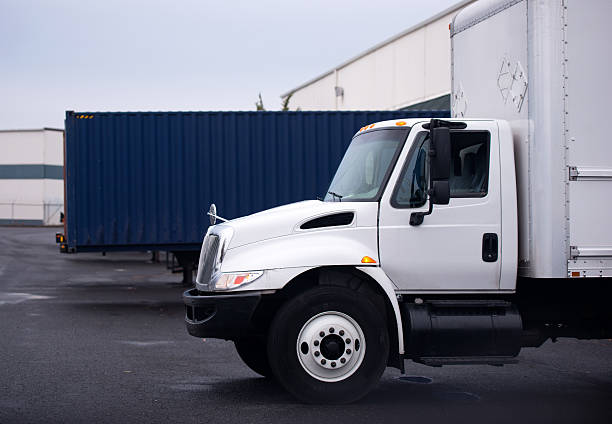 Small semi truck with box on warehouse parking lot Small economical truck with a box for the local delivery of goods on the parking lot near the store in anticipation of loading or unloading of commercial cargo. straight stock pictures, royalty-free photos & images