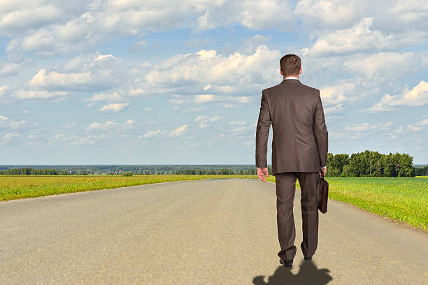 istock Businessman with briefcase walking on road ahead. Rear view 517529703