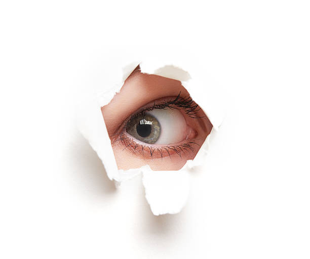istock Eye looking through  hole in  white empty paper poster 517529901