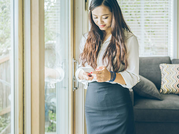 istock standing asian woman checking phone messages 517534676
